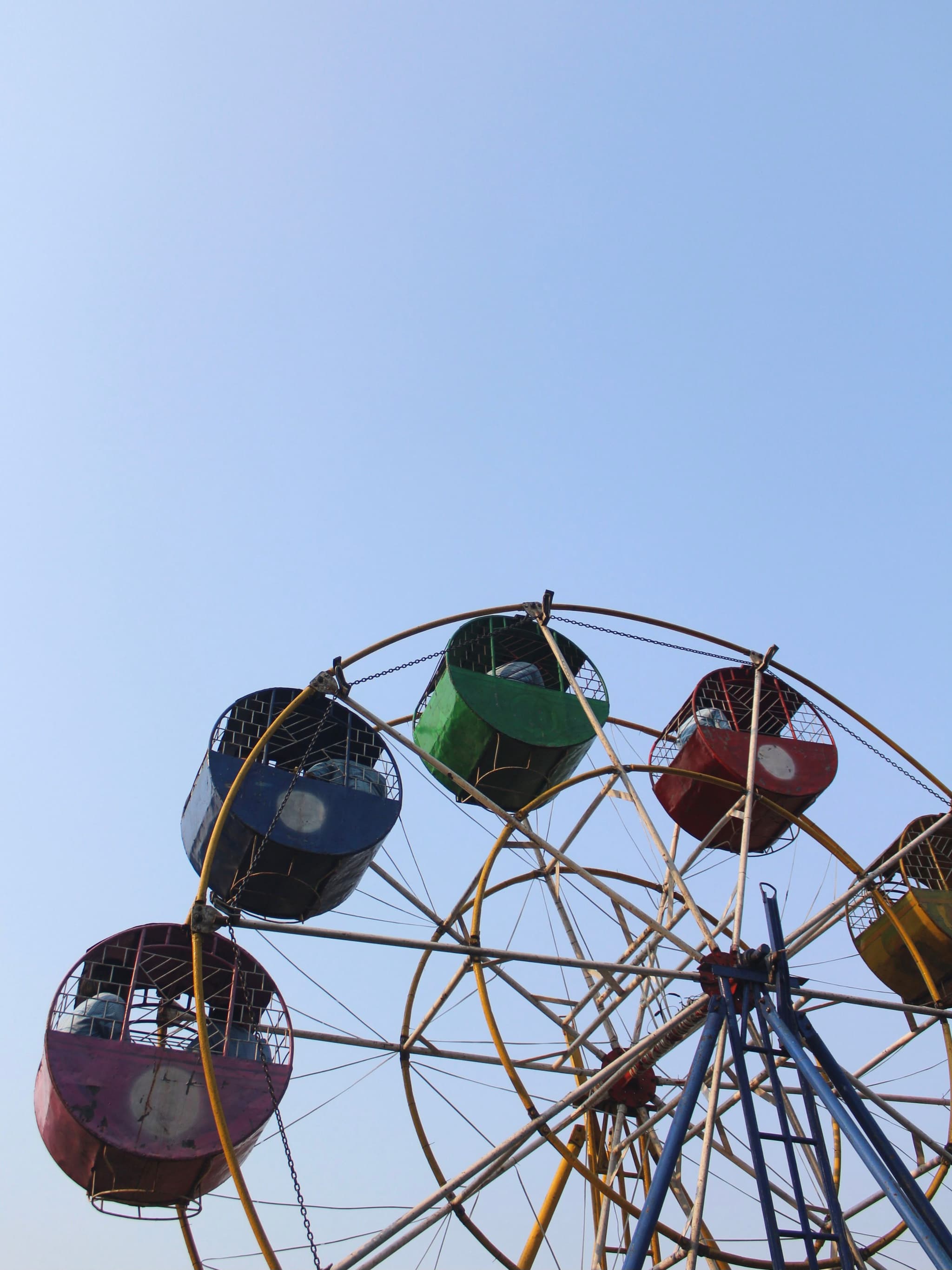 A Ferris wheel with colorful gondolas against a clear blue sky
