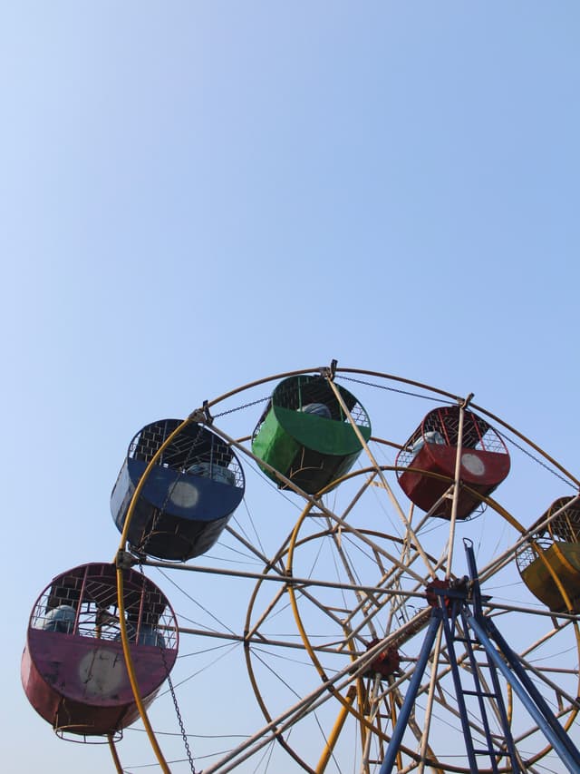 A Ferris wheel with colorful gondolas against a clear blue sky