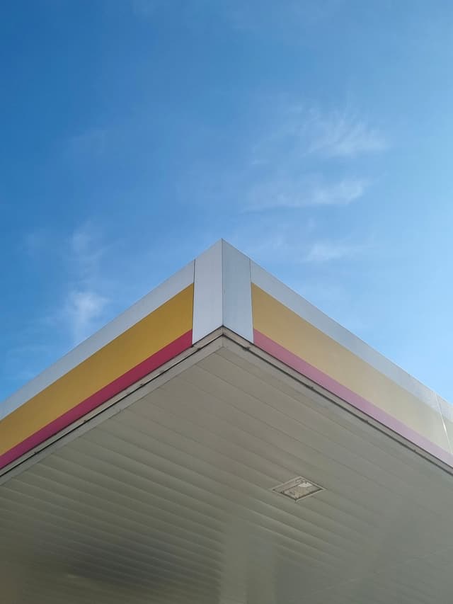 The corner of a gas station canopy with a blue sky background